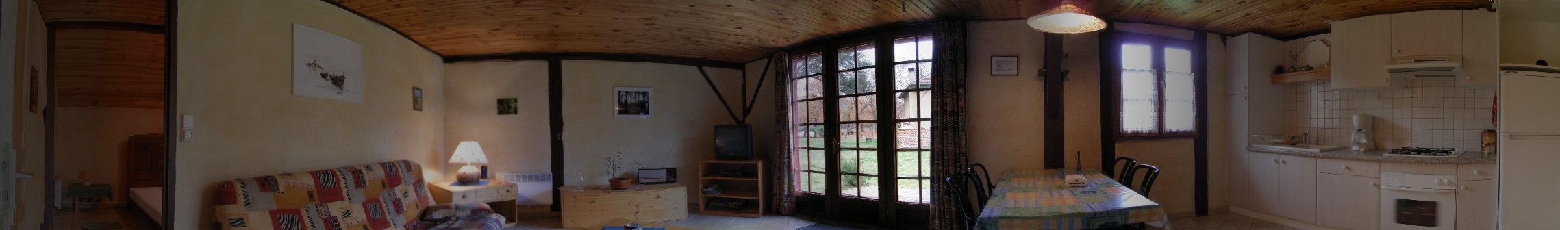 Maysouot, maison de vacances  louer dans les Landes pour 2  4 personnes. Cette photo permet d'avoir une vue panoramique  : en partant de la gauche, apperu de la chambre  coucher, puis vue gnrale du salon (clic-clac, tl) , porte fentre permet d'accder  la terrasse (salon de jardin, barbecue, ..), coin repas et cuisine. La vue, oppose  la prcdente, s'arrte juste avant la porte de la salle de bain.